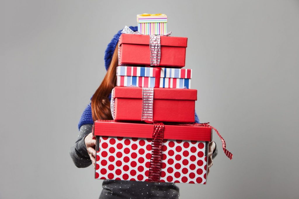 Woman Covered by Carried Gift Boxes Isolated on Gray Background.