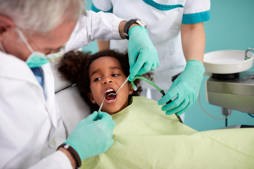 Black kid in chair on dental check up