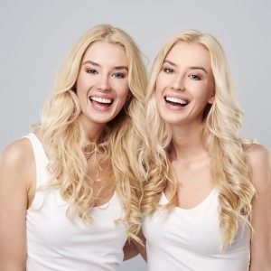 Laughing twins on the gray background